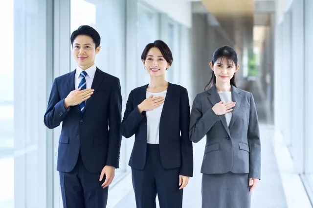 胸に手を当てる三人のビジネスパーソン